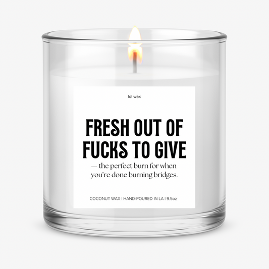 Clear glass candle with 'Fresh Out of Fucks to Give' label by lol wax, featuring a bold statement on a white background.