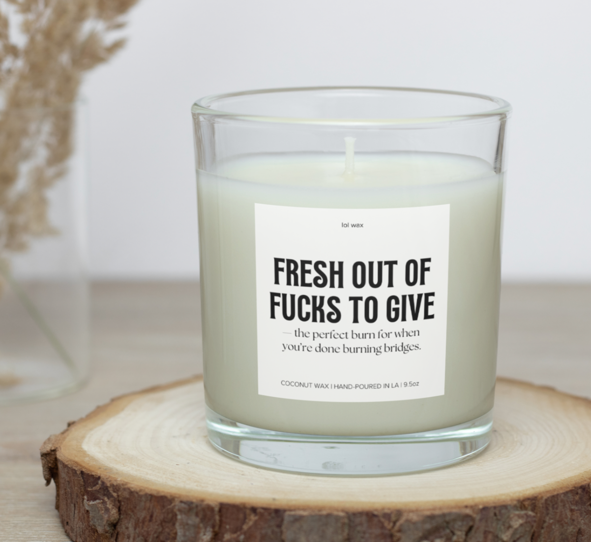 Lol wax's 'Fresh Out of Fucks to Give' candle on a wooden table, evoking a serene and earthy atmosphere.